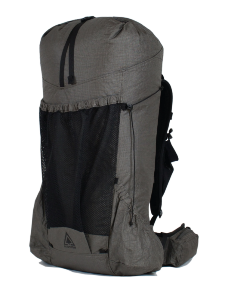 The Durston Kakwa 55 is present infront of a white background. The large grey bag is positioned to show an equal amount of its front and side. The bag has a large mesh pocket on the front, and a large pocket on the side of the bag. The bags hip belts and shoulder straps are also present in the photo.